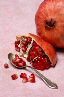 Opened pomegranate and pomegranate seeds in a spoon, Punica granatum
