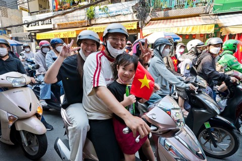 Vietnamese family with Vietnamese flag, man, woman and child traveling on a motorcycle to the 50th