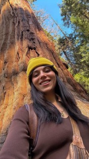 Young woman smiling and wearing a beanie, enjoying a sunny day outdoors while sightseeing and