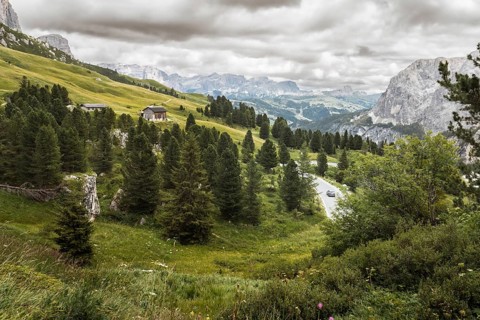 Aerial cinematic view car vehicle drives Winding mountain road through Dolomites landscape with