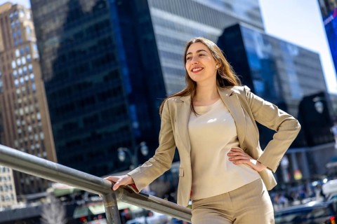 Businesswoman in a smart blazer stands outdoors in manhattan, smiling confidently as she looks