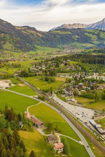 Landscape with village in a valley surrounded by green meadows and mountains in the background,
