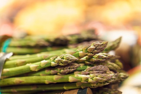 Close-up of bunches of green ripe asparagus on counter at market or grocery store in vegetable