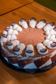 An artfully decorated chocolate cake with cream and chocolate plaques on a wooden table, Café Kuh,