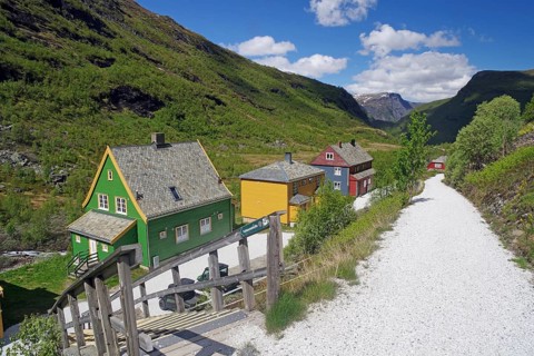Colourful houses in a small village surrounded by green mountain scenery under clear skies,