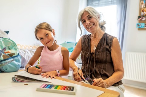 Happy grandmother and young granddaughter enjoying time together, bonding over coloring activities