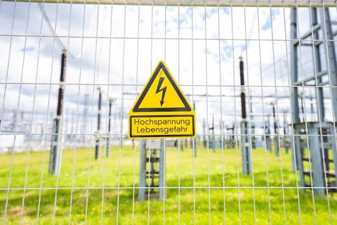 A high-voltage warning sign on a fence in a green area of the substation, Transnet BW Open