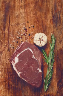 Raw steak, beef steak, rib eye steak, on a cutting board, freshly frozen, with spices and herbs, on