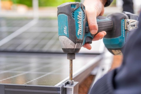 Hand holding a drill and attaching solar cell components during an installation, PV substructure,