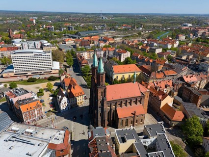 Aerial view of a city with a prominent church in the center, surrounded by roads and urban