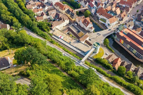 An aerial view of a city with rails and roads surrounded by green vegetation, Hermann Hesse