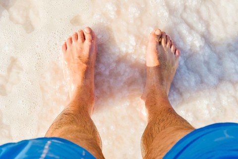 Close-up POV male tourist walking on the unique salt formations and turquoise mineral-rich waters