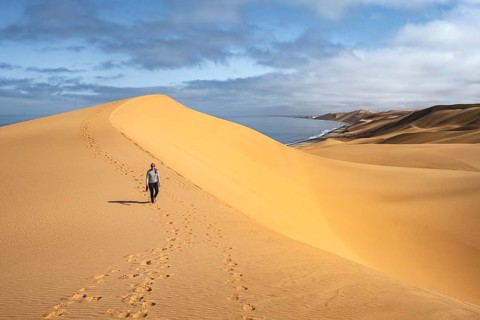 Woman running in dunes, sand dunes and sea in morning light, Atlantic coast and sandy desert with