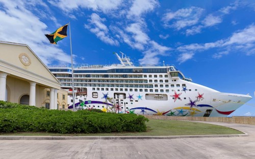 A large Caribbean cruise ship decorated with colorful star pattern on its hull docked at Falmouth