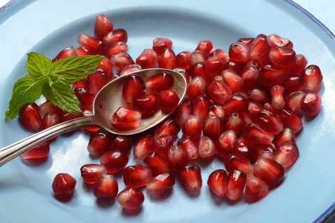 Pomegranate seeds and spoons on plate, Punica granatum