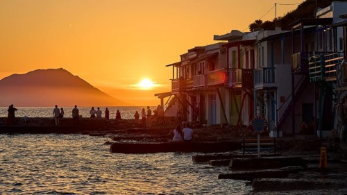 Evening atmosphere by the sea with silhouettes and colorful buildings at sunset with warm light,