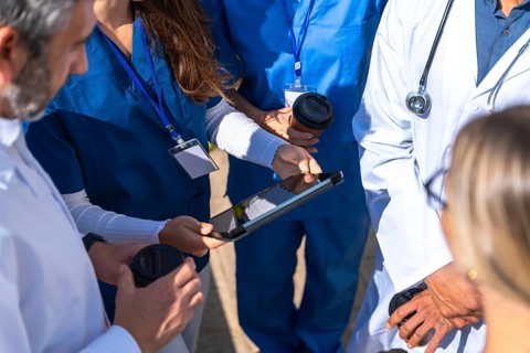 Medical team of doctors and nurses collaborating, reviewing data on a digital tablet, and