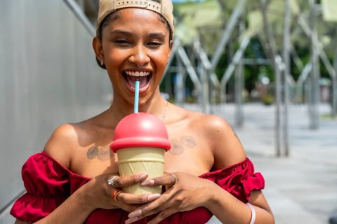 Young woman with a septum piercing and tattoos wearing an off shoulder red top and a baseball cap