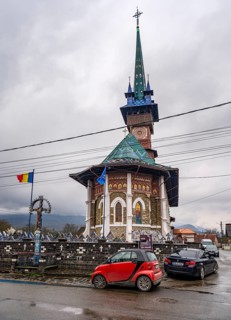 Cars in front of the Biserica Na?terea Maicii Domnului church with the cheerful Cimitirul Vesel
