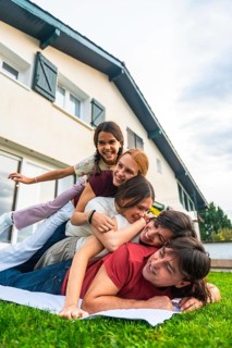 Joyful family, including a father, mother, and three daughters, creating a playful human pile on