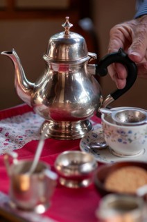 Hand touches handle of an old teapot, traditional English afternoon tea, Chapslee Hotel, former