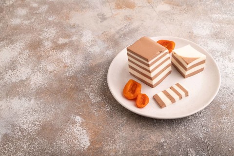 Cocoa and milk jelly with dried apricots on brown concrete background, side view, copy space,