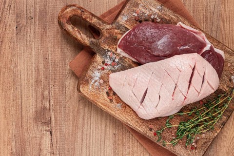 Fresh raw duck breasts, on a wooden chopping board, with herbs and spices, no people