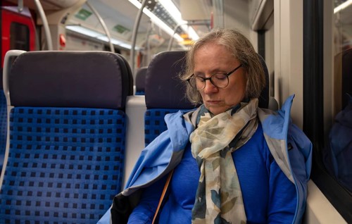 Interior view, elderly woman, glasses, sitting in subway, train, sleeping, tired, evening, night,