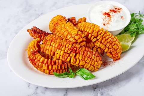 Corn ribs, with cream sauce, spices and lime, appetizer, on a white plate, homemade, no people