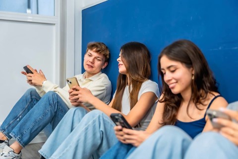 Young students sitting together on the floor against a blue wall, interacting and engaging with