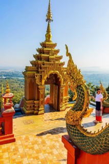 Gilded dragon figure, a gilded pagoda in the back, at the Buddhist temple Wat Phra That Don Phra