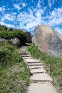 A stone staircase snakes through monumental pink granite rock formations cut around by nature on a