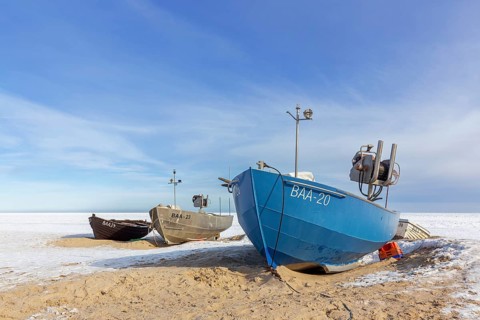 Fishing boats on snow covered beach in winter along the Baltic Sea at Baabe, Mönchgut peninsula,