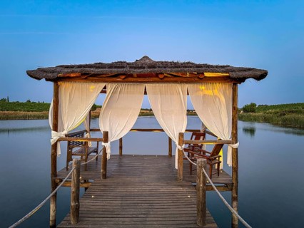 A rustic wooden pavilion with white curtains stands over a tranquil lake, Pedrógão, Beja, Portugal