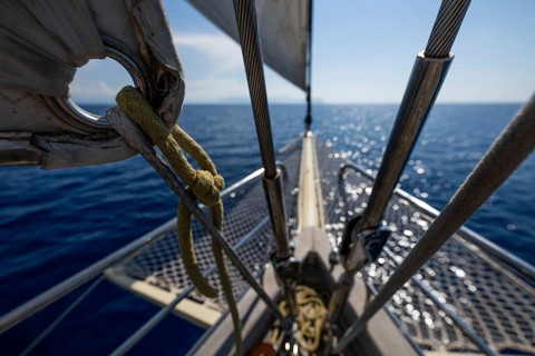 Looking forward from a sailboat, over deep blue water with light waves, Aeolian or Aeolian Islands,