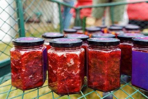 Collection of hexagonal jars with black lids filled with homemade strawberry jam or preserves in a