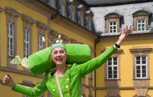 An artistic performance by a fairytale-like costumed stilt walker, visually impressive walking act,