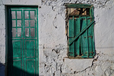Abandoned green door and green window in an old weathered stone wall, Trypiti, Tripiti, village,