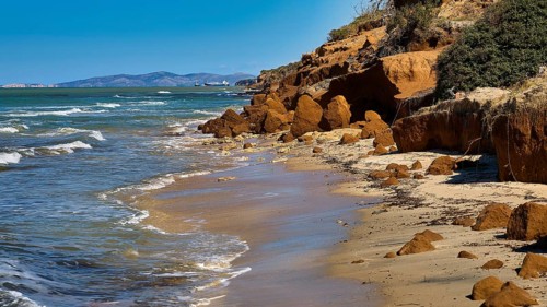 Vulcanic Beach, natural rocky coast with sea and waves, blue sky in the background, Kos,