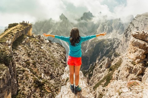 Aerial view Woman hiker on viewpoint with Open Arms Overlooking Cadini di Misurina Peaks Dolomites