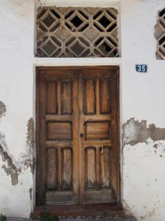 Old wooden door in white wall with peeling paint and house number, Fataga, Barranco de Fataga, Gran