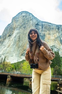 Young woman smiling while standing at valley view in yosemite national park, carrying a camera and