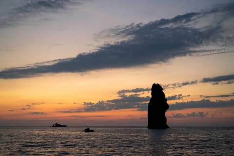Impressive rock and anchored boat just after sunset, near Filicudi, Aeolian or Aeolian Islands,