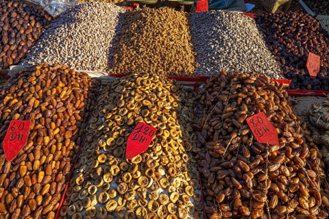 Various dried dates, figs, pistachios, nuts and almonds are on display for sale at a sales stand,