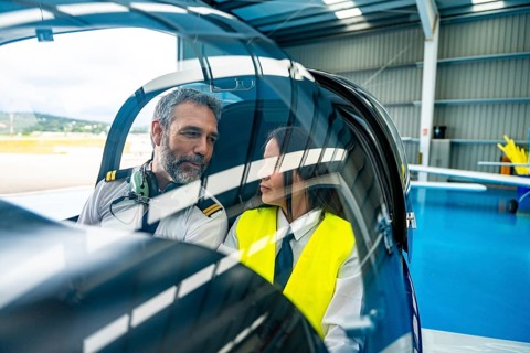Experienced aviation instructor providing flight training to a young female pilot student,