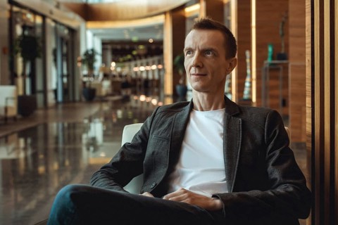 Man in jacket sitting calmly in modern hotel lounge with warm lighting and stylish decor