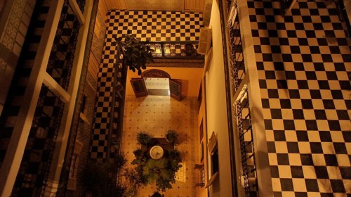From above, a checkerboard-like Moroccan courtyard of a riad in the old town, Medina, with balcony