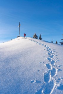 Active senior woman hiking with snowshoes on the Nagelfluh mountain chain ini the Allgaeu Alps near