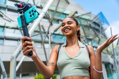 Young biracial woman actively recording content for her online followers, using a mobile phone with