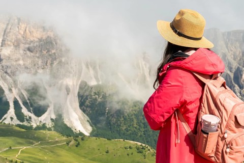 Close up asian female hiker with backpack and straw hat looking at misty mountain peaks deep valley